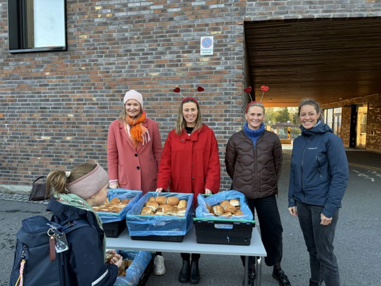 En gruppe mennesker som står utenfor en bygning med mat på et bord En gruppe mennesker som står utenfor en bygning med mat på et bord