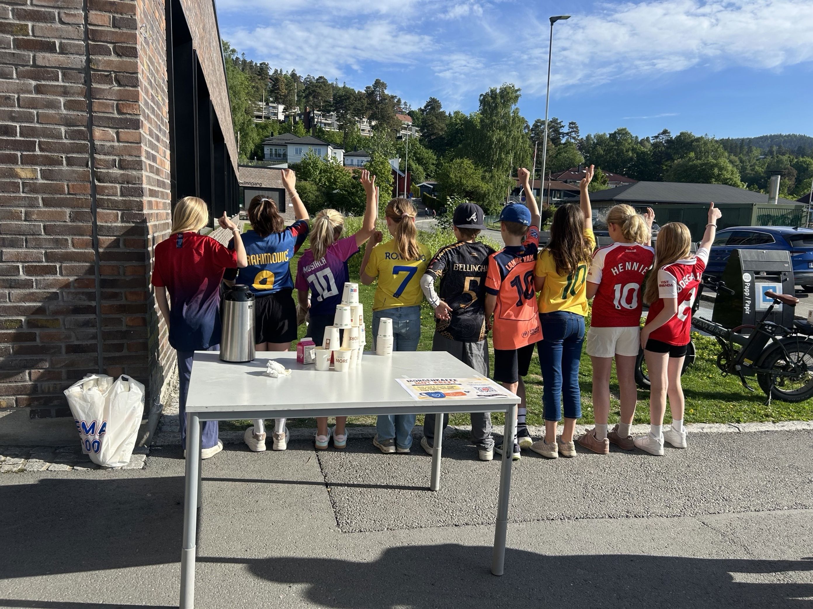 en gruppe barn som står rundt et bord utenfor en gruppe barn som står rundt et bord utenfor